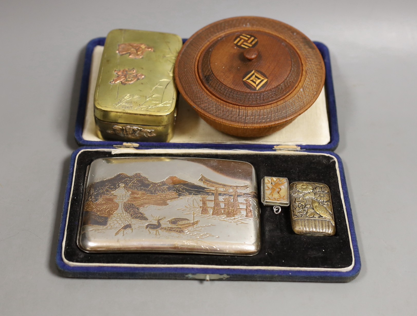 A Japanese sterling cigarette case, vesta, a locket, box and carved circular bowl and cover, bowl and cover 11 cms diameter.